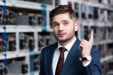handsome young businessman with creative idea pointing up at cryptocurrency mining farm clipart