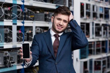 failed young businessman showing smartphone at cryptocurrency mining farm clipart