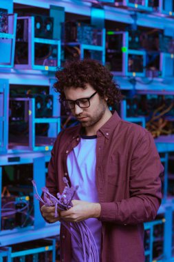 handsome computer engineer with ethernet wires at ethereum mining farm clipart