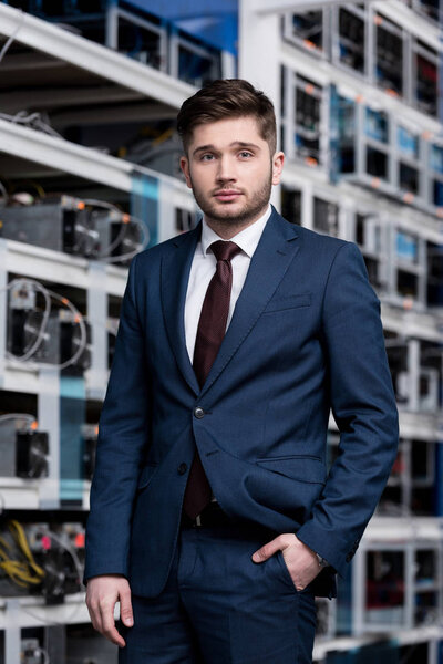 handsome young businessman in stylish suit at cryptocurrency mining farm