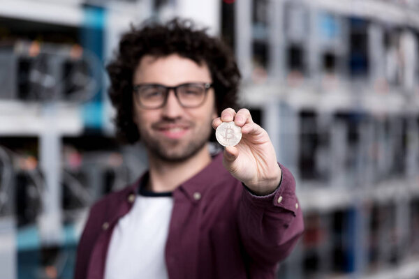 handsome computer engineer holding bitcoin at cryptocurrency mining farm
