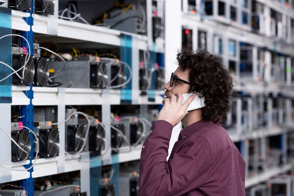 young computer engineer talking by phone at ethereum mining farm