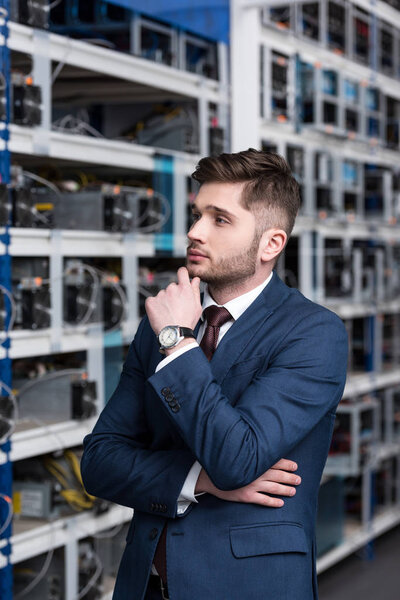 thoughtful young businessman with hand on chin at ethereum mining farm