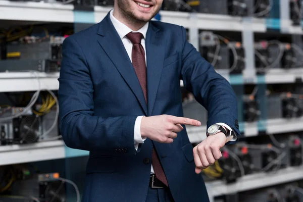 Ethereum マイニング ファームで腕時計を指して笑顔の実業家のショットをトリミング — ストック写真