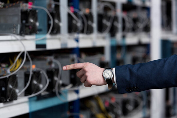 cropped shot of businessman pointing at cryptocurrency mining farm