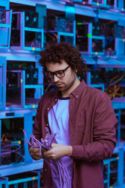 handsome computer engineer with ethernet wires at ethereum mining farm