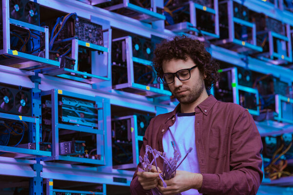 young computer engineer with ethernet wires at ethereum mining farm