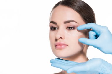 close-up shot of doctor touching face of woman with dotted line for plastic surgery isolated on white clipart