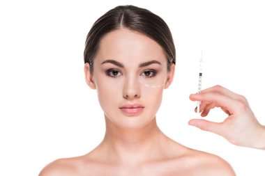 beautiful young woman with dotted line drawn on face for plastic surgery and hand holding syringe isolated on white clipart