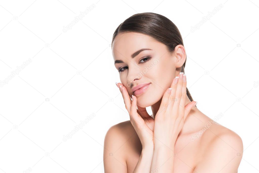 smiling young woman touching her face and looking at camera isolated on white