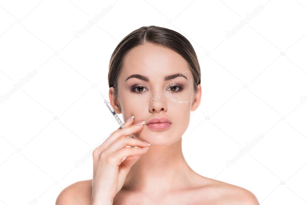 young woman with dotted line drawn on face for plastic surgery holding syringe isolated on white