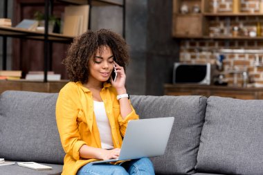 çalışma ve koltukta evde telefonla konuşurken mutlu kadın