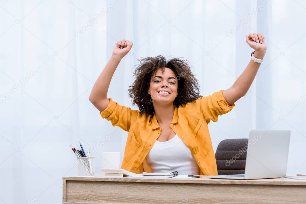 beautiful young woman performing victory dance at workplace