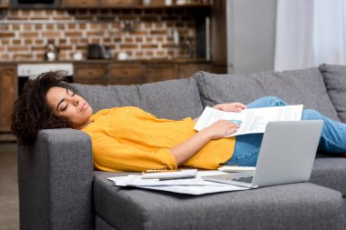 tired african american woman sleeping on couch after work at home