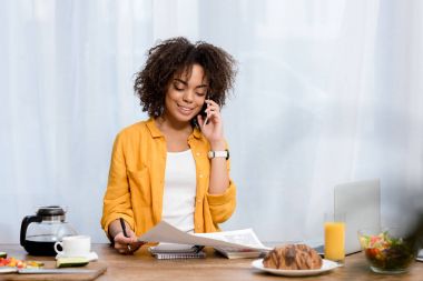 evde çeşitli gıda ile masada çalışan genç Afro-Amerikan kadın