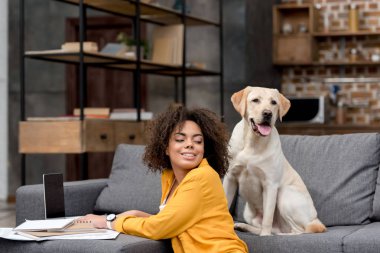 güzel ve genç birbayan dizüstü evde kanepede oturan köpeğini süre ile çalışma