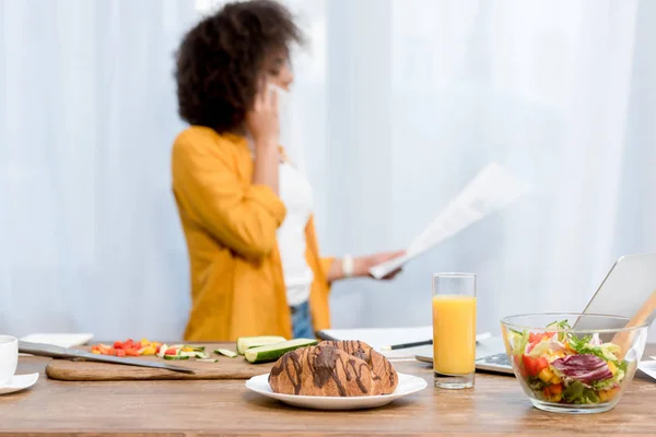 Jonge Vrouw Praten Telefoon Het Lezen Van Documenten Met Voedsel — Gratis stockfoto