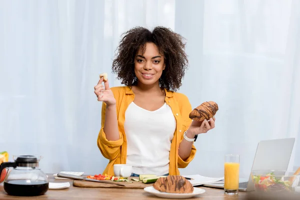 Bela Jovem Mulher Comer Croissant Enquanto Trabalhava Casa — Fotografia de Stock