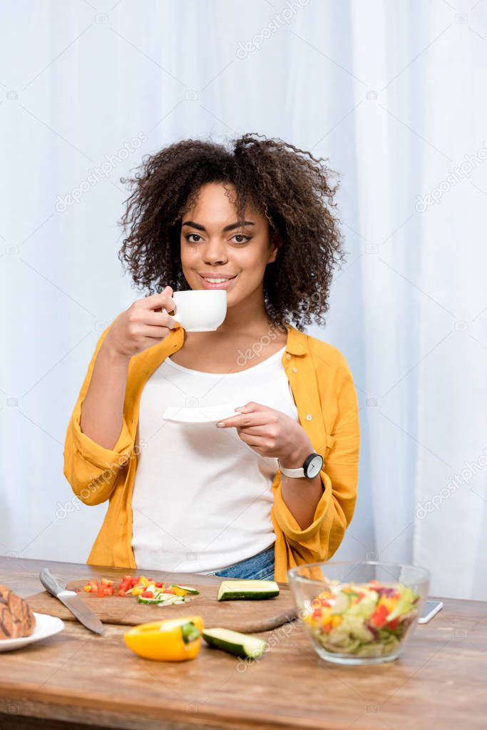 young  mixed race woman drinking coffee and taking diner at home