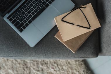 Laptop ile gözlük ve gri sandalyeye kitaplar