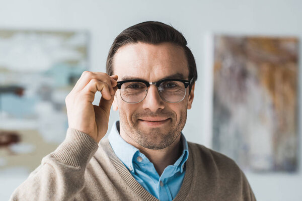 Smiling adult man fixing his eyeglasses