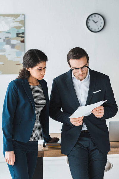 Businessman and businesswoman looking at contract papers in office