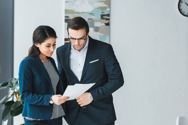 Business colleagues looking at contract papers in office