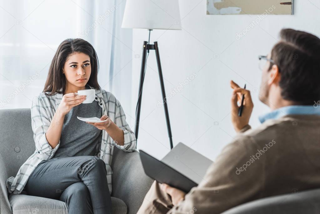 Woman drinking coffee and listening to male doctor recommendations