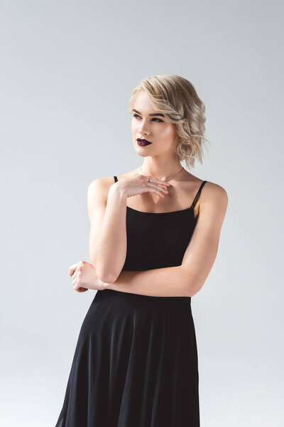 attractive blonde girl posing in elegant black dress, isolated on grey 