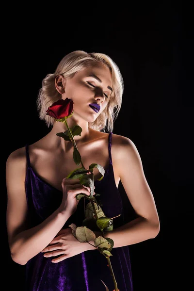 温柔的金发女孩摆在紫色的礼服与红玫瑰 孤立的黑色 — 图库照片