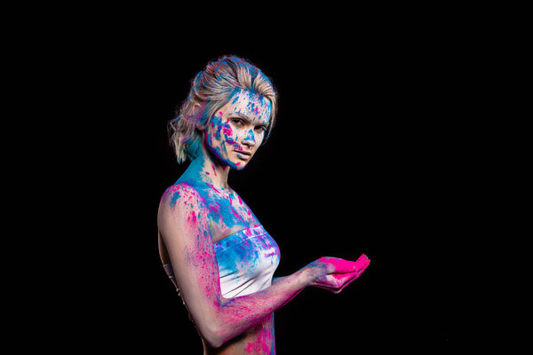 beautiful girl posing in pink and blue holi powder, isolated on black