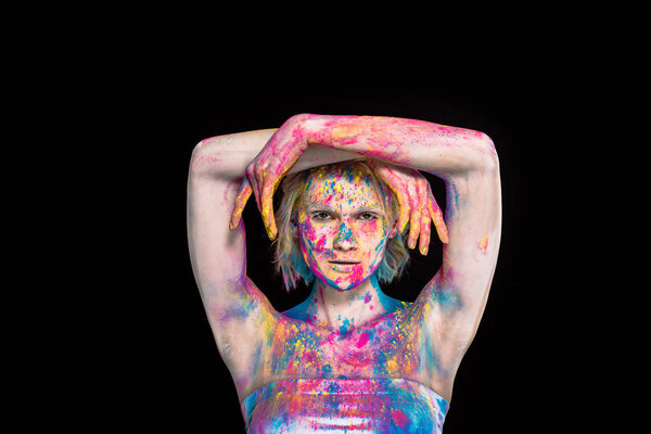 young stylish woman posing in colorful holi powder, isolated on black