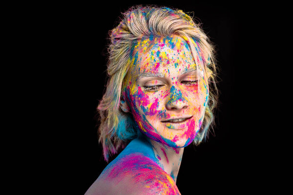 beautiful happy girl in colorful holi powder, isolated on black