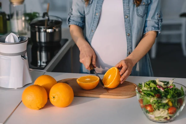 Pregnant cutting oranges — Stock Photo, Image