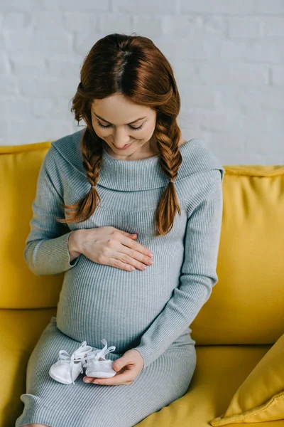 Attractive Pregnant Woman Touching Abdomen Looking Newborn Shoes Living Room — Stock Photo, Image