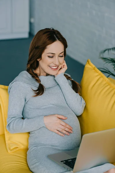 Schwangere schaut auf Laptop — kostenloses Stockfoto