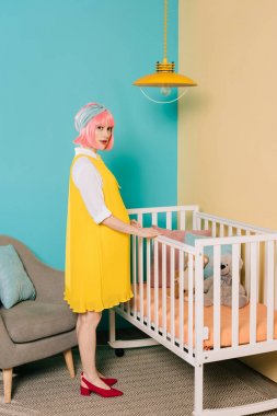 Kadın pembe saç ayakta bebek yatağı yakınındaki ile hamile PIN Retro tarz