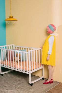 retro yan görünüm pembe saç konumu Bebek karyolası yakın olan kadın hamile PIN çocuk odasında tarz.