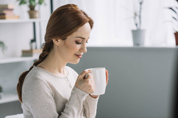 side view of beautiful pregnant woman drinking tea at home