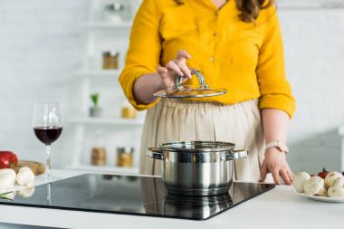 kapak pan mutfak elektrikli soba yakınındaki üzerinden tutan kadın kırpılmış görüntü