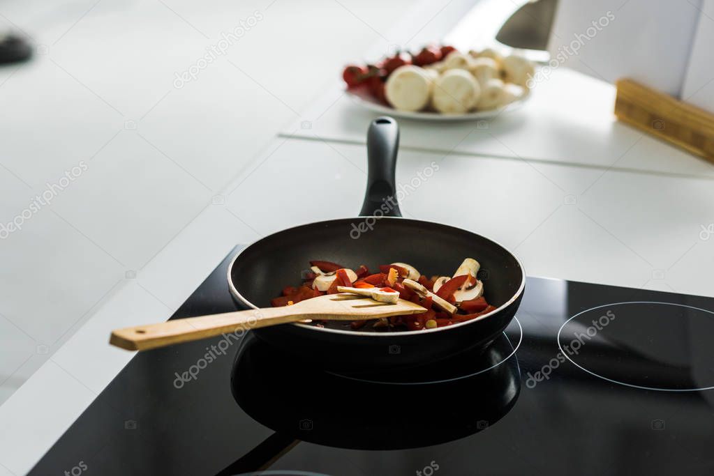 frying pan with delicious vegetables on electric stove in kitchen
