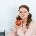 Schöne Frau schaut in der Küche auf den Apfel