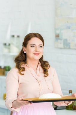 ekmek pişirme ve uzak mutfakta seyir için hamur tepsiye tutan kadın