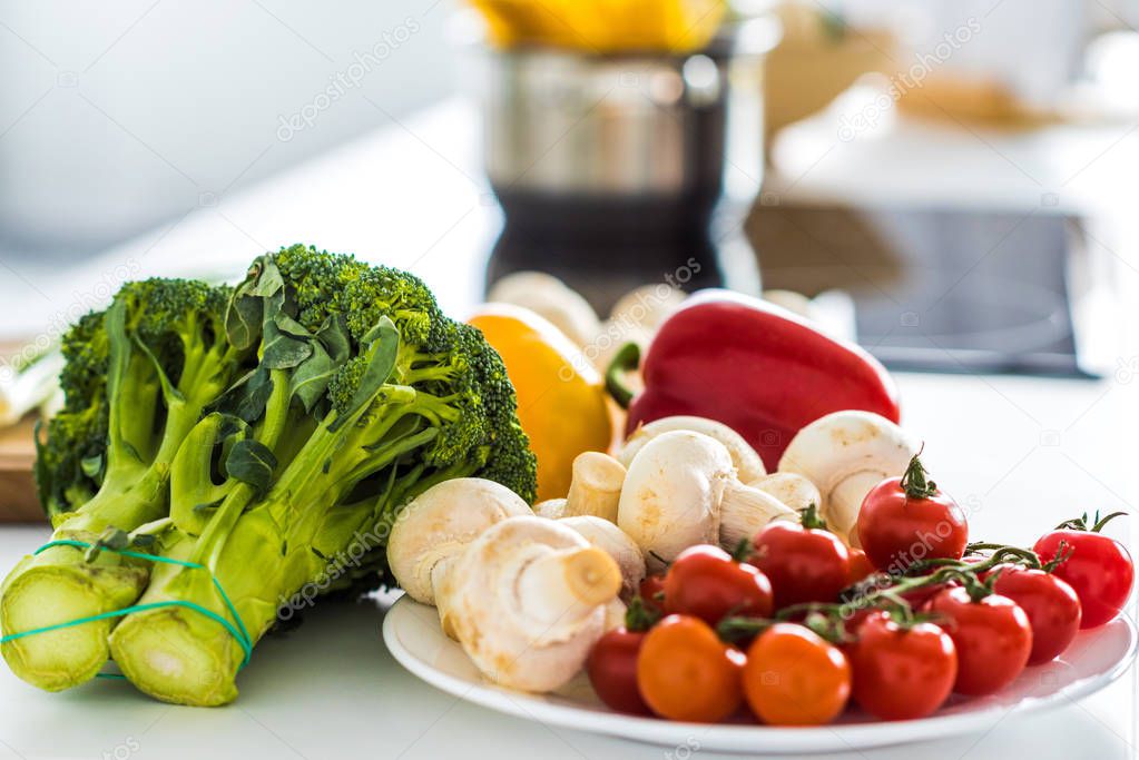 broccoli, mushrooms and cherry tomatoes on plate in kitchen