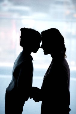 Anne ve kızı evde alınları ile dokunmadan siluetleri