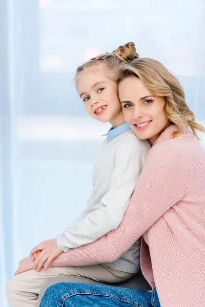 Sonrientes Madre Hija Abrazando Mirando Cámara Casa —  Fotos de Stock