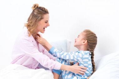 Anne evde yatakta gıdıklama mutlu kız gülümseyerek