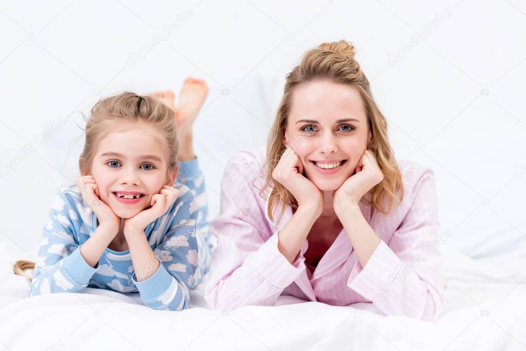 mother and daughter resting chins on hands and looking at camera at home