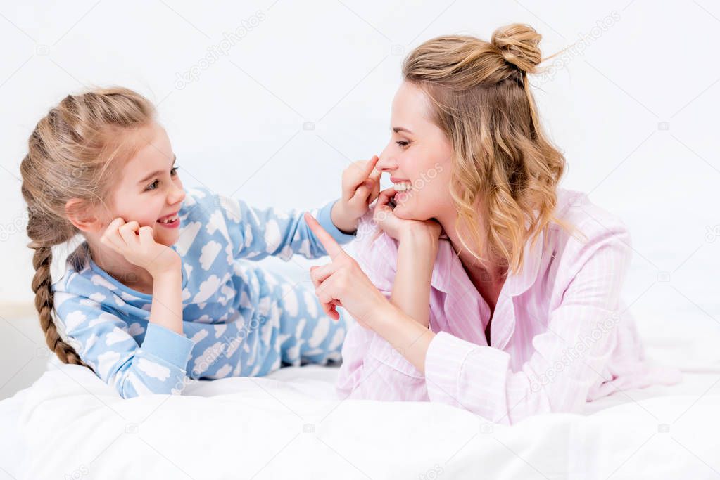 mother and daughter having fun and touching noses with fingers at home