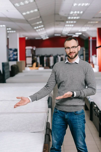 Retrato Cliente Masculino Óculos Apontando Para Colchões Dispostos Loja Móveis — Fotografia de Stock